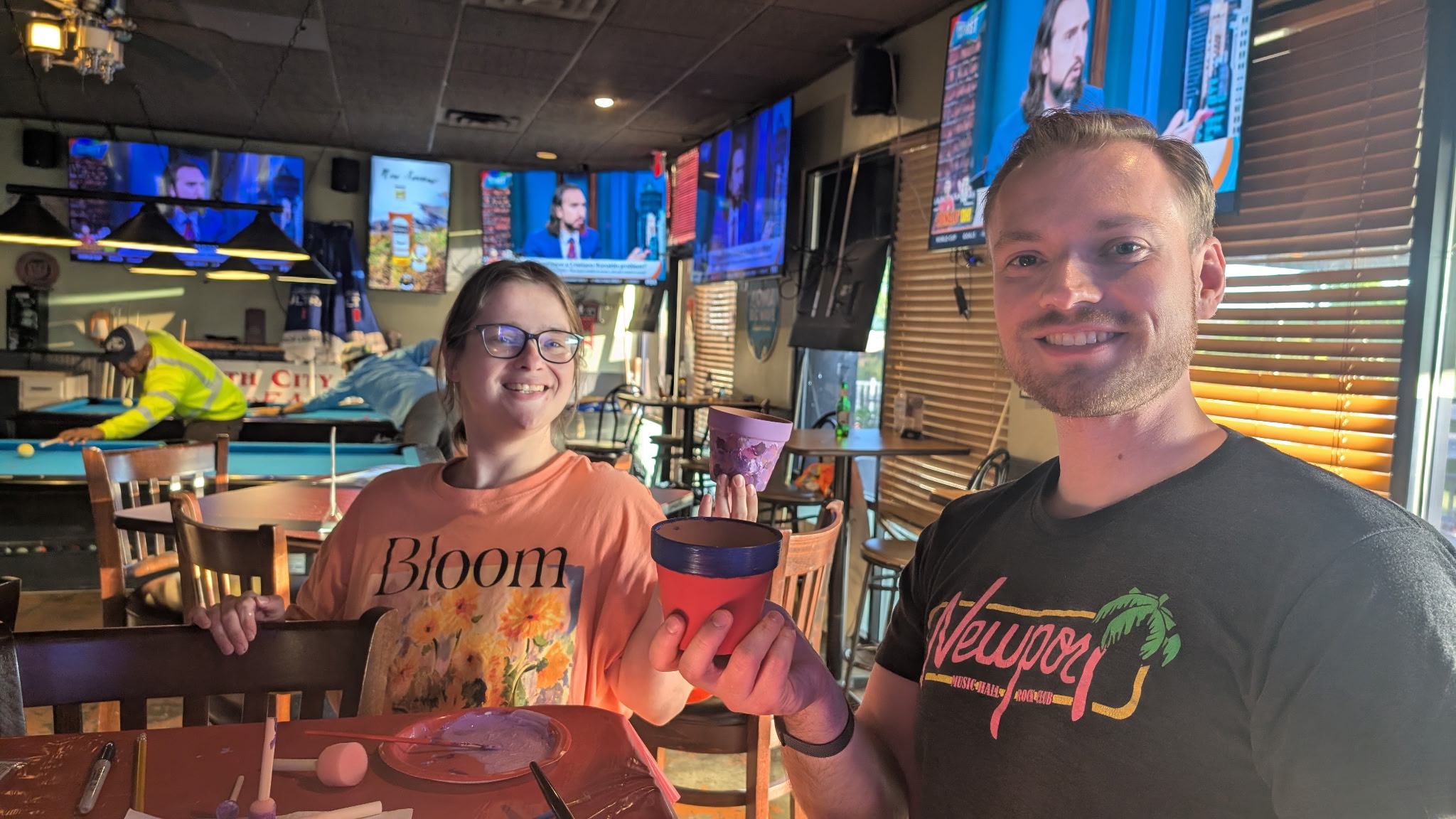 Guests posing with painted pots near the pool tables